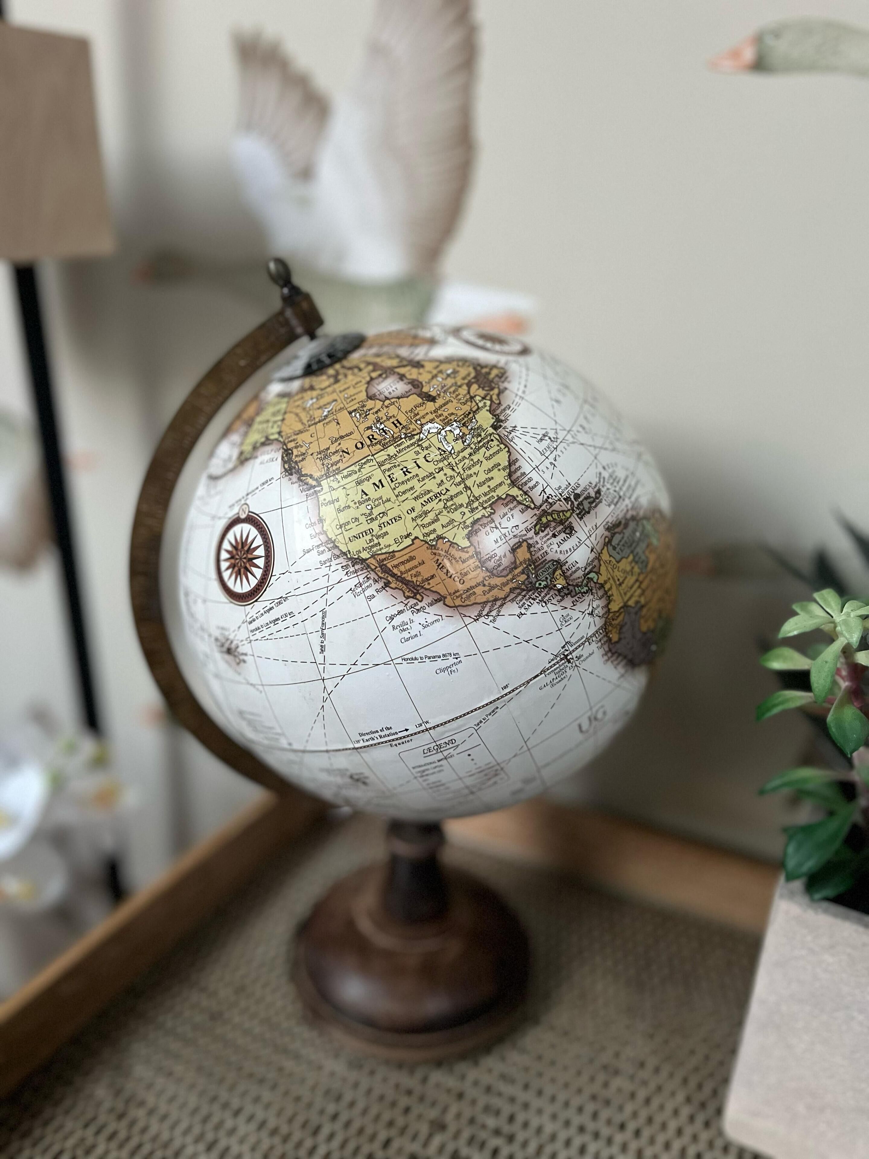 Un globo sobre un atril de madera con una rosa de los vientos, sobre una superficie con textura.