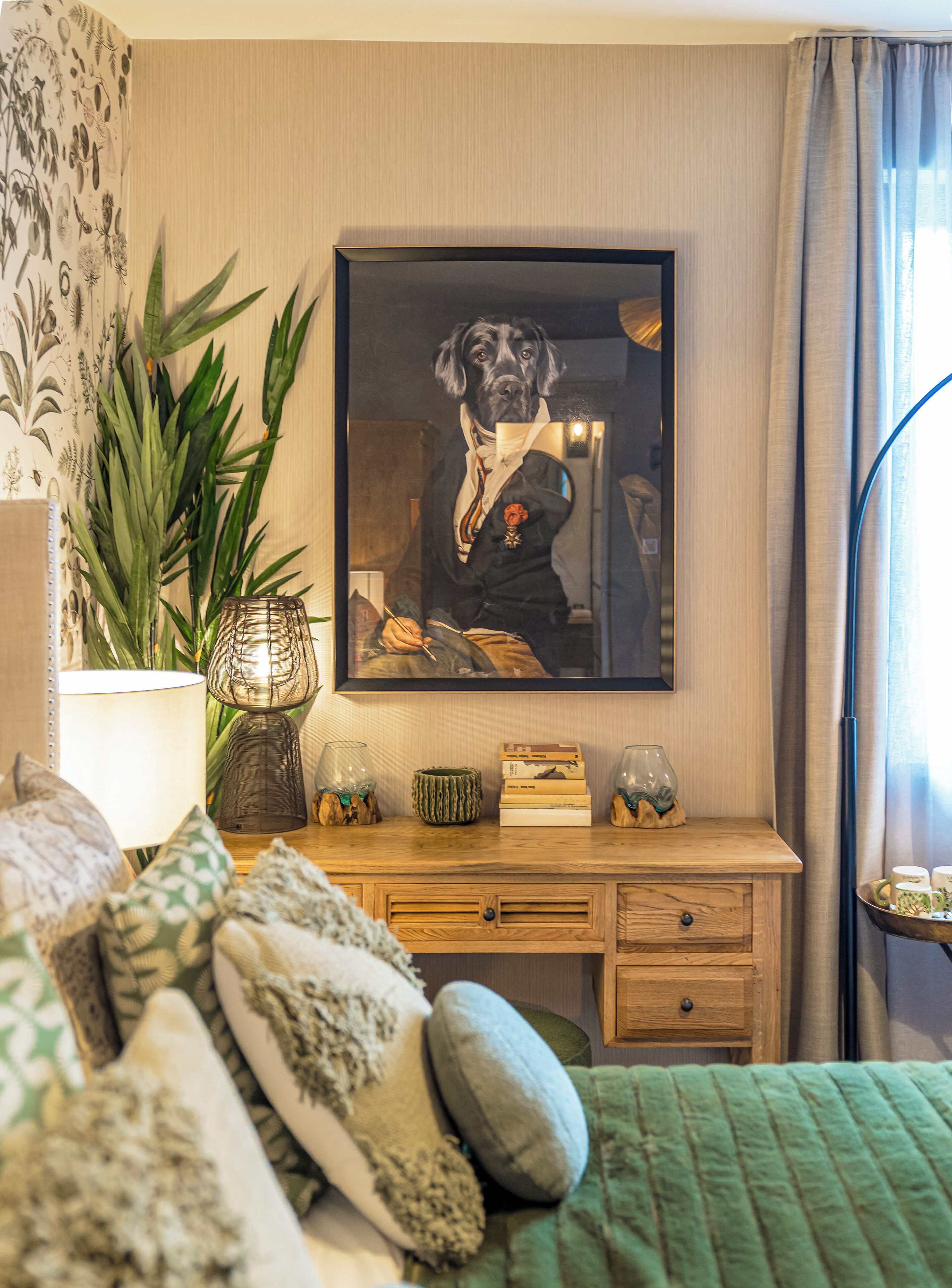 A bedroom with a bed, a desk, a lamp, a potted plant, and a framed picture on the wall.