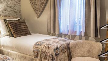 A bedroom with a large bed, a hanging light fixture, a window with curtains, and a fluffy rug.