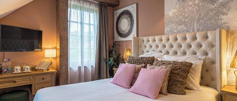 Un dormitorio con una cama grande, un escritorio con silla, un televisor de pantalla plana y una ventana con cortinas.