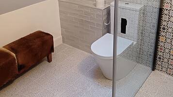 Un baño moderno con inodoro blanco, un banco marrón y un tragaluz.