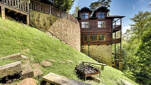 Una casa de madera rústica con un muro de piedra de contención, una terraza de madera y una chimenea de piedra.