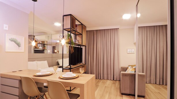 Uma sala de estar moderna com uma mesa de jantar de madeira, duas cadeiras, um sofá, uma televisão e uma estante de livros.