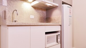 Cozinha com micro-ondas embutido, pia e geladeira.