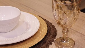 Uma tigela branca e um copo de vidro transparente sobre uma mesa de madeira com um jogo americano trançado.