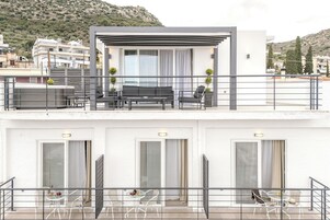 Un edificio moderno de dos pisos con un balcón que incluye mobiliario exterior y un área de estar cubierta.