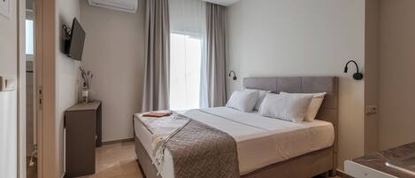A modern bedroom with a bed, bedside table, and a TV mounted on the wall.