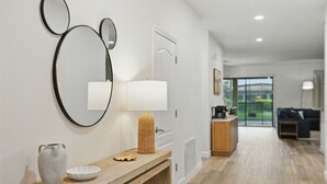 A modern living room with a wooden console table, a white vase, a bowl, a lamp, and wall-mounted mirrors. - The Moon Valley Oasis - Spacious 7-bedroom house with Pool, and Game room. (Four Corners)