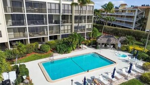 Un hotel con piscina, sillones de descanso y una estructura de techo de paja.