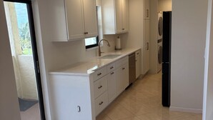 Una cocina moderna con armarios blancos, un lavamanos de acero inoxidable y un refrigerador negro.