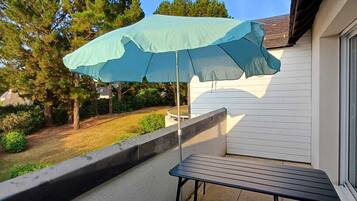 A balcony with a table and a light blue umbrella.