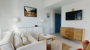 Ein Wohnzimmer mit einer Couch, einem Couchtisch, einem Fernseher, einem Schrank und einer Tür zu einem anderen Raum.