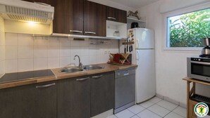 A modern kitchen with dark wooden cabinets, a white refrigerator, and a window with a view of greenery.