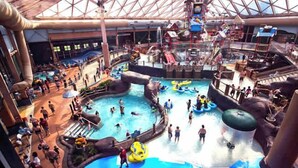 An indoor water park with multiple pools, slides, and water play areas.