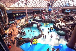 Parque acuático interior con múltiples piscinas, toboganes y zonas de juegos de agua.