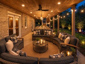 Un patio exterior cubierto con zona de comedor, asientos y luces ambientales.