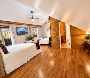 Habitación de hotel moderna con dos camas, piso de madera, un ventanal con vistas y una pared de madera.