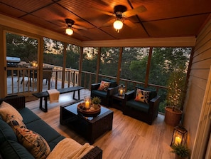 A covered outdoor seating area with a view of the outdoors, a grill, and a dining table.