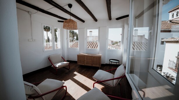 A spacious room with large windows, a wooden floor, and a ceiling with exposed beams.