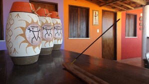 A room with a wooden table, three decorative vases, and a black cane leaning against the wall. - Hostel Muiraquitã (Aracati)