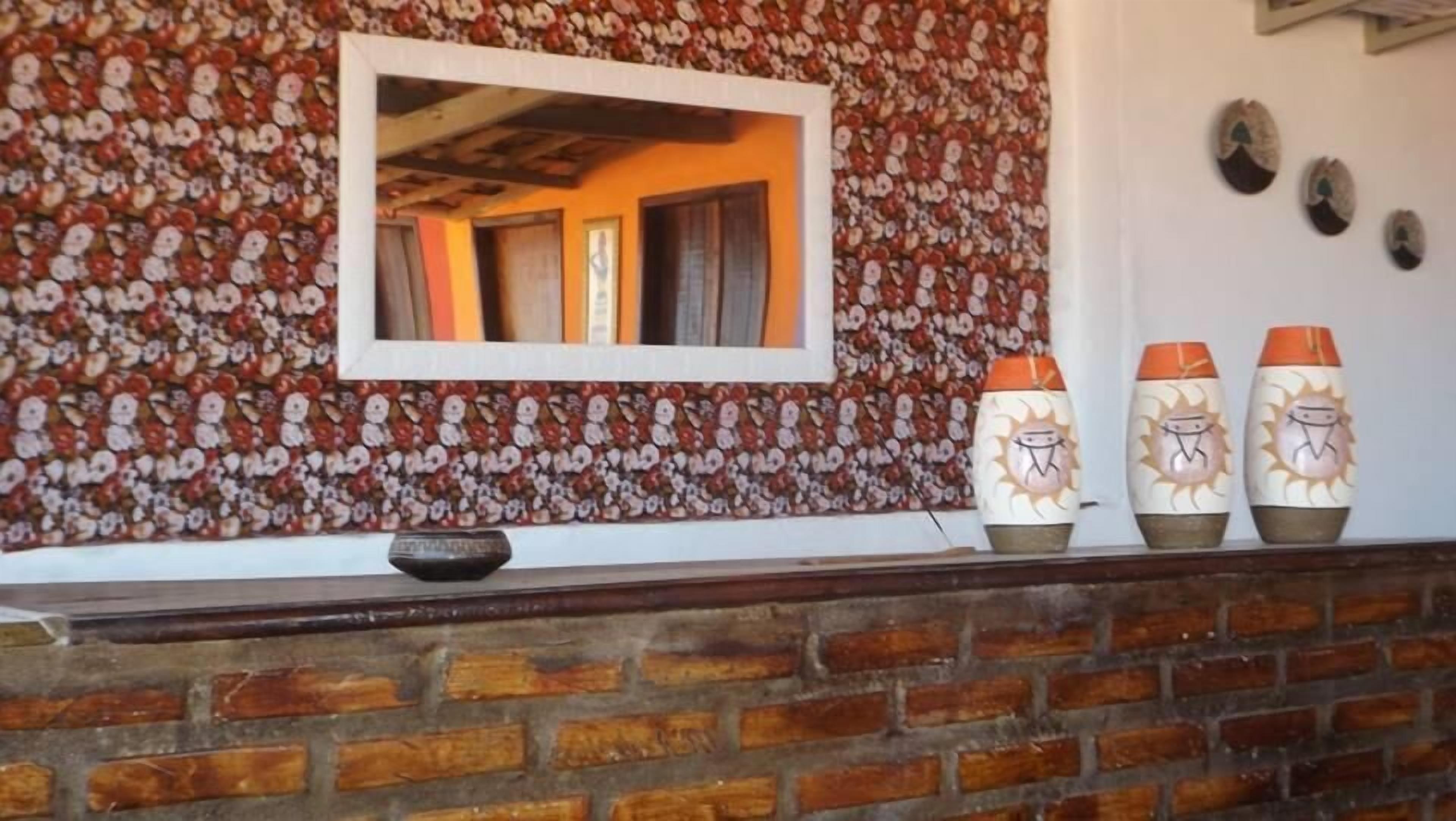 Una pared de ladrillo con un diseño decorativo y un cuadro colgado encima.