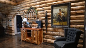 A log cabin interior with a wooden bar, a black upholstered armchair, and a framed painting on the wall. - Our beautiful lodge near Albany, MO is sure to please! Perfect for large groups (Albany)