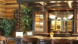 A bar area with three ornate bar stools, a wooden ceiling, and a mirror reflecting the bar. - Our beautiful lodge near Albany, MO is sure to please! Perfect for large groups (Albany)