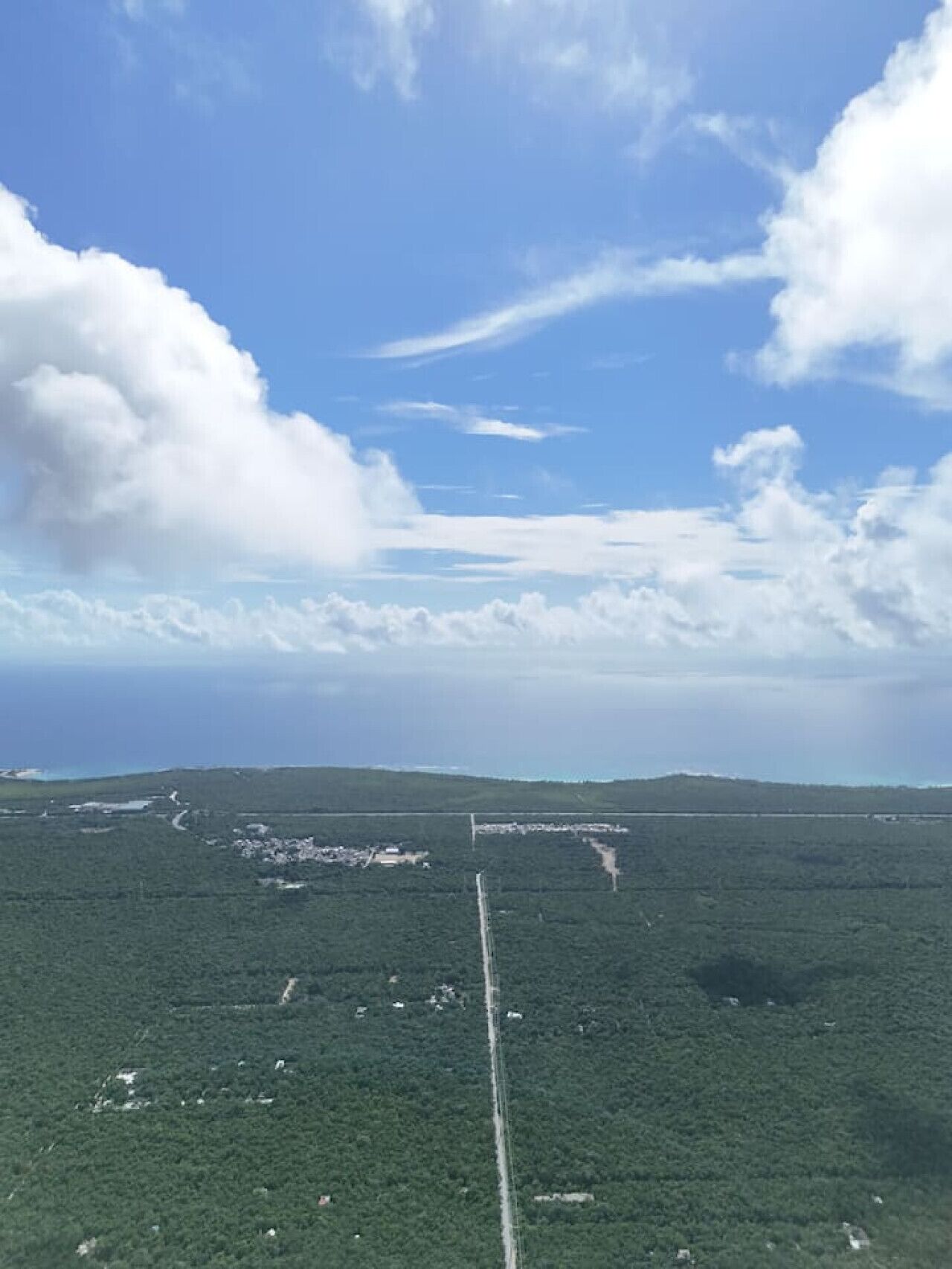 A wide view of a forested landscape with a clear sky and a few clouds.