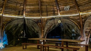 Un pavillon abrité, doté d’un toit de chaume, de bancs et d’un sol en béton.