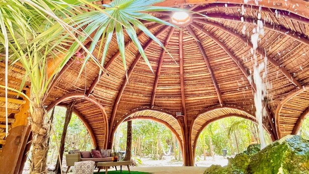 Un espace extérieur abrité, doté d’un toit de chaume, de bancs et d’une table centrale.