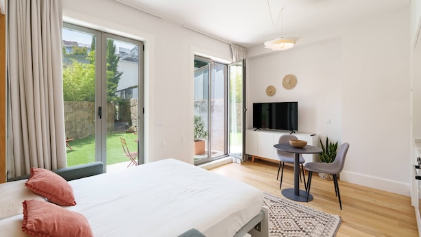 Een moderne slaapkamer met een groot bed, een televisie, een klein tafeltje en een stoel.