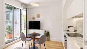 Een moderne keuken met een televisie, eethoek en grote ramen.
