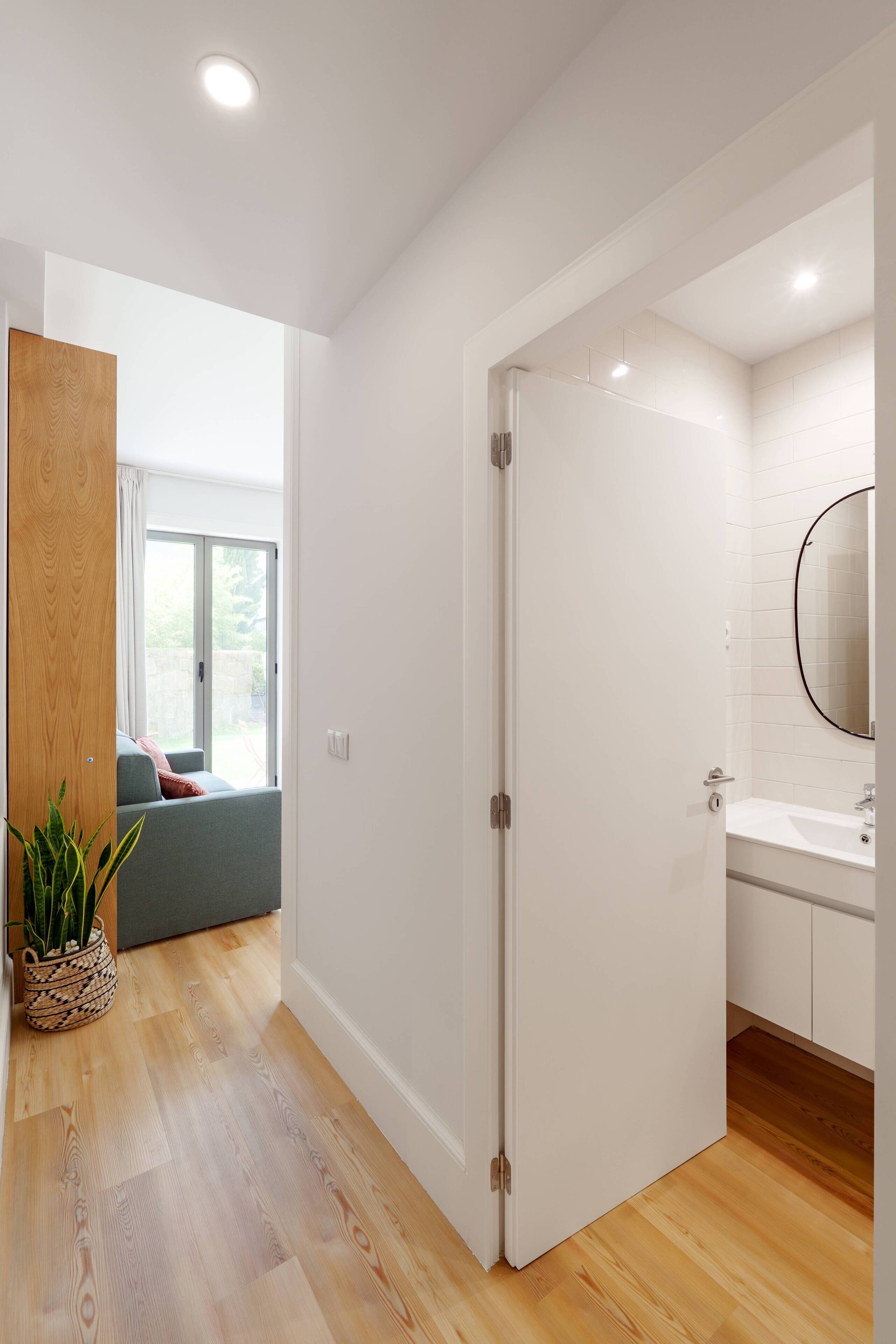 Une salle de bain moderne avec un lavabo blanc, un miroir et un plancher en bois.
