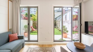 Een moderne woonkamer met een grijze bank, een geweven mand en een televisie op een dressoir.