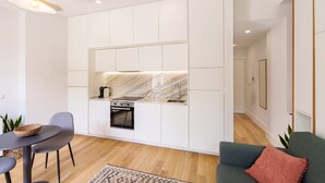 Een moderne keuken met witte kasten, een marmeren spatwand en een inbouwoven.