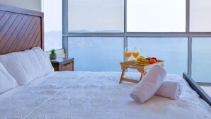 A bed with white linens, a wooden headboard, and a nightstand with a plant. A tray with fruit and two glasses of orange juice is on the bed. - Stunning Lake-view Villa at Coatepeque - Wifi, A/C (El Congo)