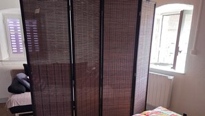 Una habitación con cama, techo de madera, ventana con persianas y vistas al exterior.