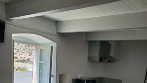 Una cocina compacta con ventana, microondas, lavamanos y una mesa de comedor de madera.