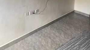 Habitació amb televisió de pantalla plana penjada a la paret, presa elèctrica i terra de rajola gris.