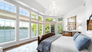Quarto com cama grande, lustre, cômoda e espelho.