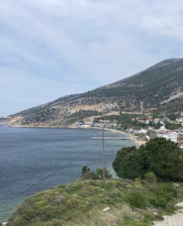 A coastal town with a beach, houses, and a hill with sparse vegetation. - Kalemi Pansiyon (Marmara)