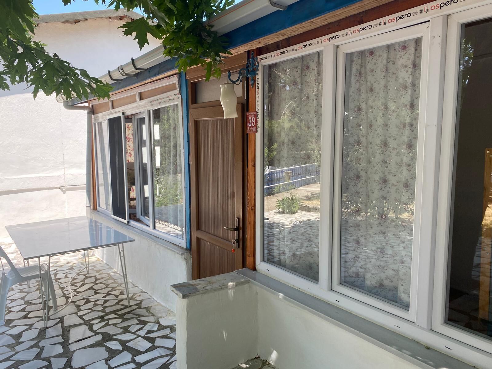 A room with a tiled floor, a window with a floral curtain, and a door with a sign indicating a price of 39.