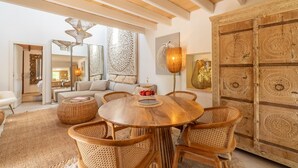 Un vaste salon agrémenté d’une table ronde en bois entourée de chaises en osier, d’un grand panneau mural décoratif et d’une armoire en bois de style traditionnel.