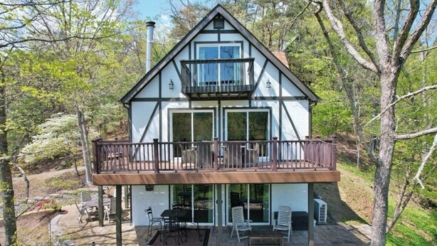 A two-story house with a balcony, large windows, and a patio area with outdoor furniture. - Cozy 3bedroom home w AC, WiFi, in a golf retreat, nestled in the scenic mountain (Basye)