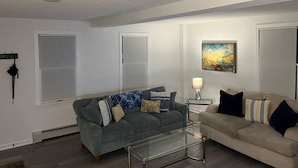A living room with two sofas, a glass coffee table, and a painting on the wall.