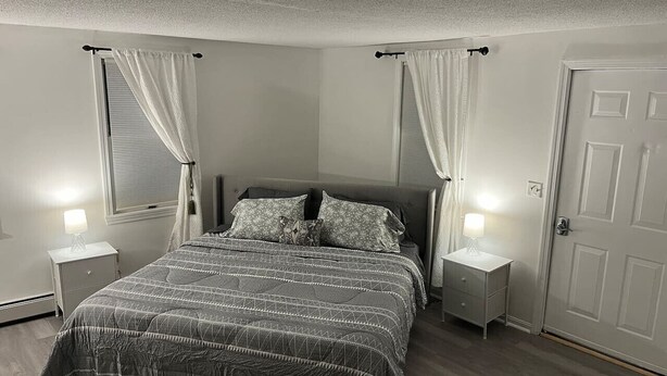 A bedroom with a bed, two bedside tables, a door, and curtains.