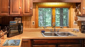 A kitchen with wooden cabinets, a double sink, a microwave, and a coffee maker. - Belgrade Lake house with Dock! (Rome)