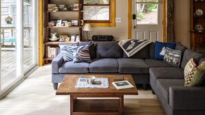 A cozy living room with a grey sectional sofa, a wooden coffee table, and a bookshelf filled with various items. - Belgrade Lake house with Dock! (Rome)