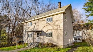A two-story house with a front porch, a chimney, and a small attached garage. - Nothing Fancy Older Apt~Walk to Downtown~ King Bed (Dover)