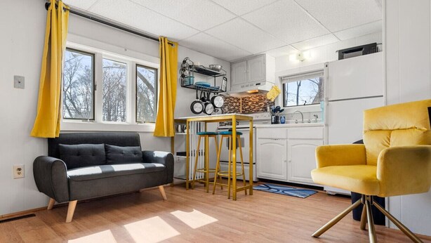 A compact living space with a sofa, yellow armchair, kitchen area, and large windows. - Nothing Fancy Older Apt~Walk to Downtown~ King Bed (Dover)